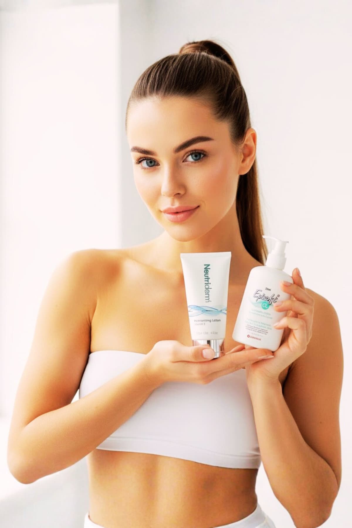 Close-up of young woman applying moisturizer on her face in bright bathroom, morning skincare routine hero image